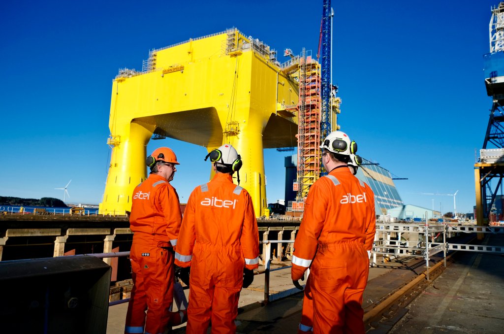 Bilde av tre ansatte hos Aibel foran deres anlegg i Haugesund 