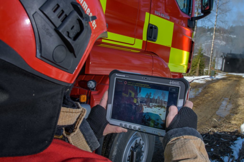 Bilde av brannmann foran en brannbil som holder en Ipad hvor den nye løsningen Bouvet har vært med å utvikle synes. 