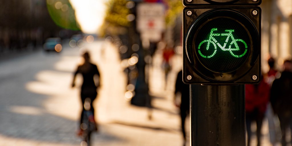Sustainable transport. Bicycle traffic signal, green light, road bike, free bike zone or area, bike sharing with cyclist and bike on the background 