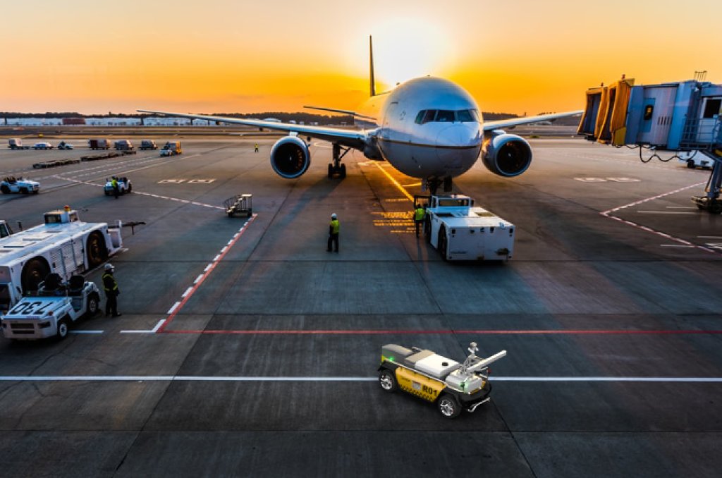 Bilde av en rullebane på en flyplass, hvor du ser et fly ved siden av roboten til Roboxi som Bouvet har fått tatt del i utviklingen av. 