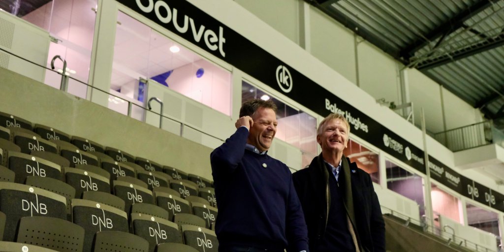 Bilde av Terje og Bjarte fra Bouvet på tribunen hos Oilers. I bakgrunnen ser man Bouvet-logoen. 