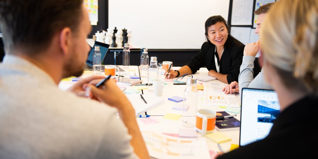 På bildet ser vi flere personer sitte rundt et bord og diskutere