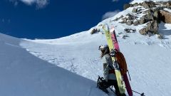 Bilde av Heidi med ski på ryggen på en fjelltopp 